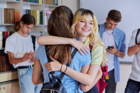 Two school girlfriends teenagers are welcome, meeting, smiling, rejoicing inside school