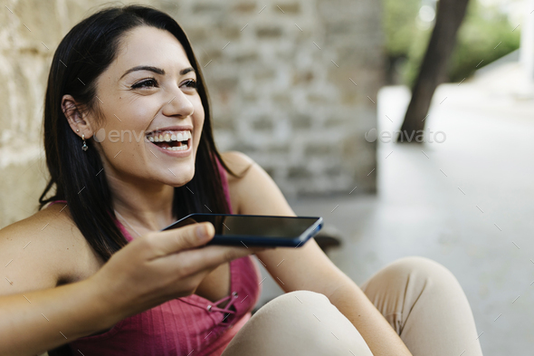 Young trendy woman sending voice message