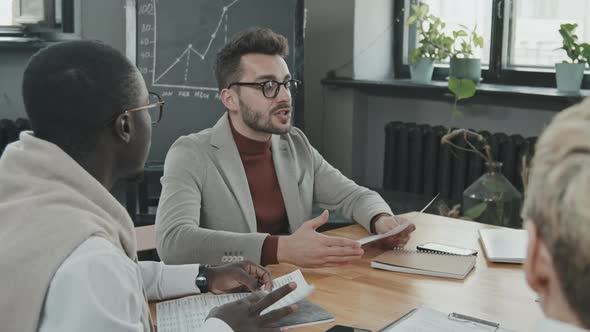 Businessman Discussing Documents with Multi-Ethnic Partners alt