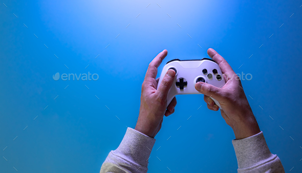 Male hands hold a gamepad on a blue background, copy space. - Stock Photo - Images