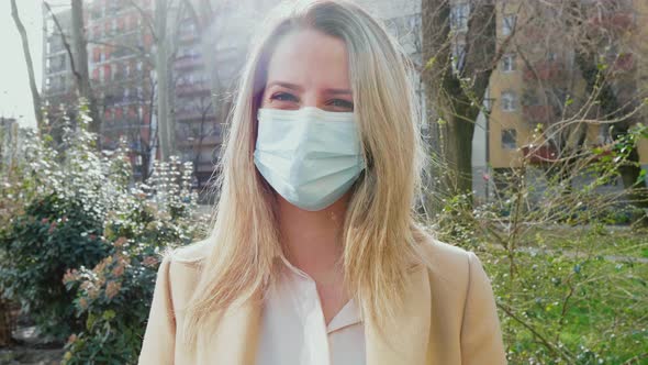 Portrait of blonde young woman wearing face mask outdoors, Milan, Italy