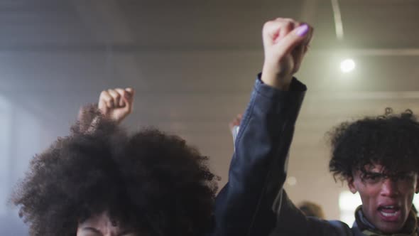 Diverse group of people wearing face masks holding protest signs shouting raising fists alt