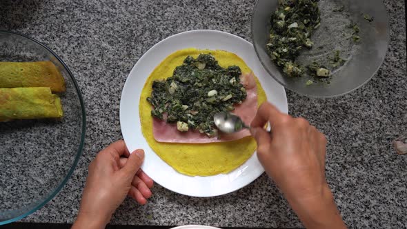 Preparing Cannelloni At Home. Filling Pasta Sheet With Ham Slice And Spinach Mixture. overhead alt