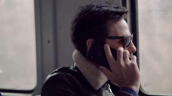 Elegant Man In Sunglasses Using Mobile Phone And Call To Friends. Man Talking On Smartphone In Train alt