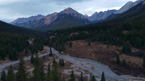 Creek and mountain range with pine tree forest approaching alt
