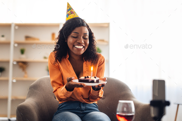 African Woman Holding Birthday Cake Video Calling Via Phone Indoors