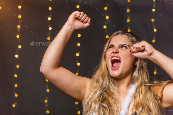 A euphoric woman screaming and raising hands with blurred background