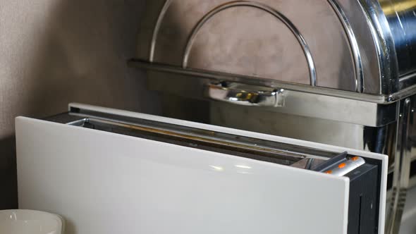 Hotel Serves Buffet for Breakfast. Roasted Delicious Bread Jumping Out From White Toaster. Frying alt