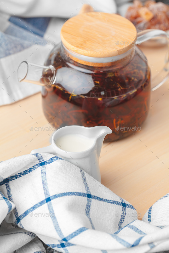 Earl Grey tea in glass tea pot on wood plate close up