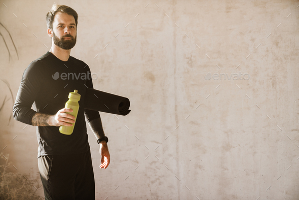 Midsection Of Man Holding Water Bottle While Standing Against Wall stock  photo