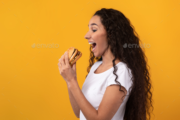 Funny Latin Lady Holding Burger Biting Sandwich At Studio
