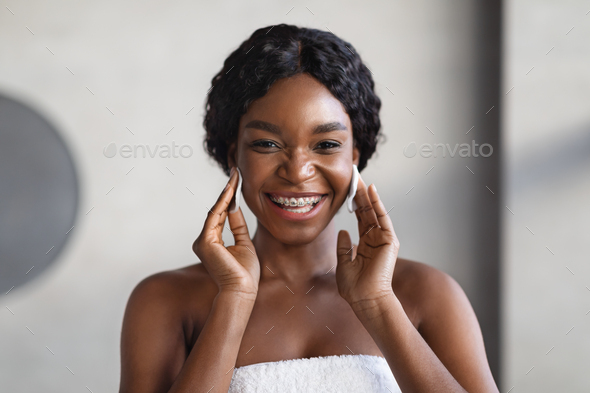 Attractive young black woman using cotton pads