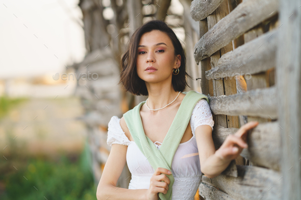 Asian Woman Posing Near A Tobacco Drying Shed Wearing A White Dress And Green Wellies Stock 