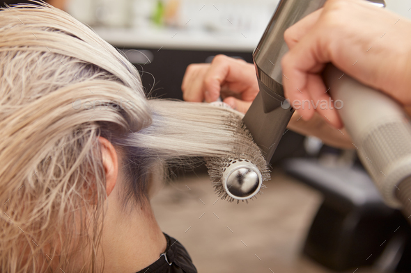 Hairdresser blow drying woman hair with round brush Stock Photo by  friends_stock