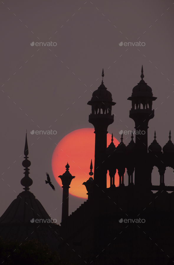 Close up of finials and lanterns on roof of Indian monument at full moon.