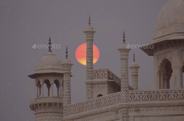 Close up of finials and lanterns on roof of Indian monument at full moon.