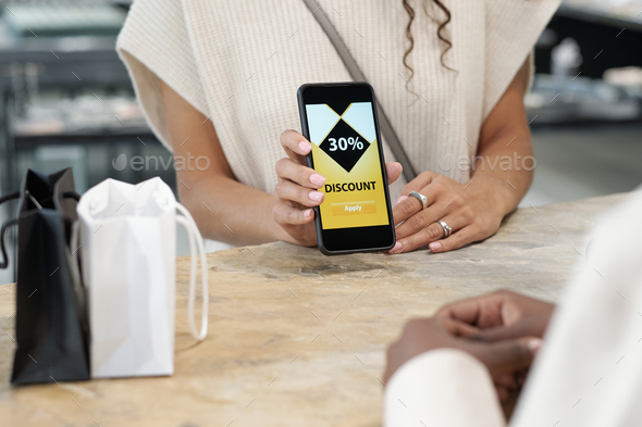 Hands of young consumer showing discount coupon in smartphone - Stock Photo - Images