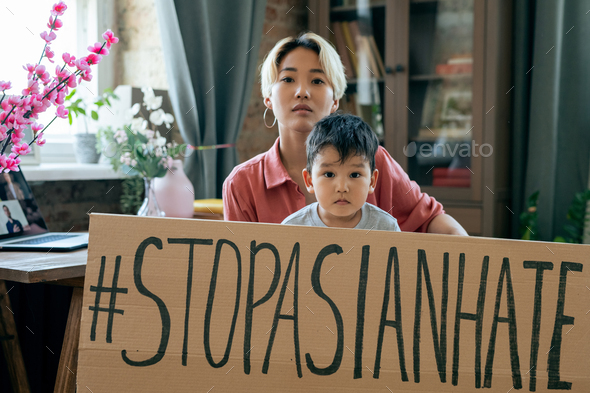 Young Asian woman and her little son holding slogan against national hate and dicrimination