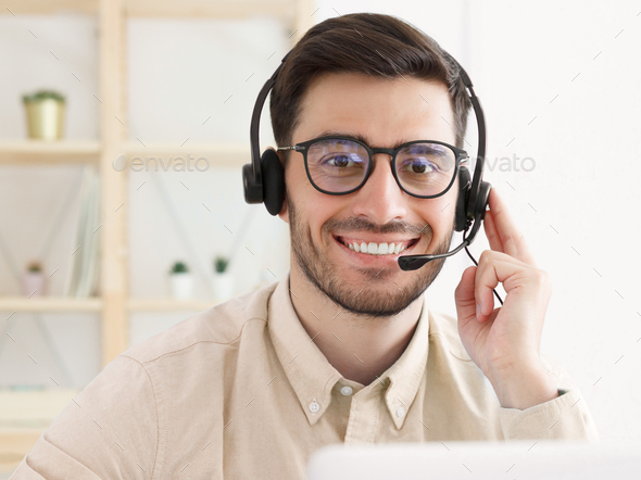Portrait of office guy working in customer support, wearing glasses and headset - Stock Photo - Images