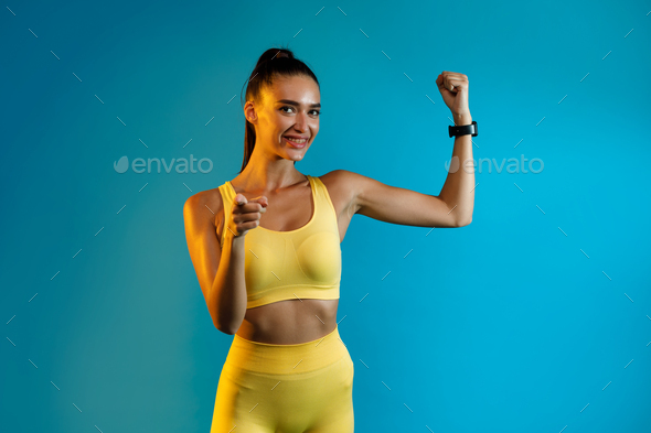 Fitness Lady Showing Biceps Pointing Finger At Camera, Blue Background
