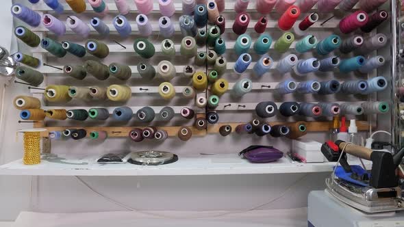 Set of Colored Threads for Sewing on Reels on the Wall in the Sewing Workshop alt