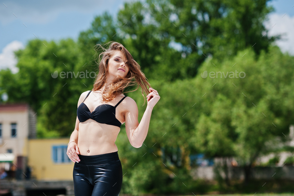 Portrait of gorgeous sexy brunette girl model in black bra and tight  leather pants Stock Photo by ASphotostudio