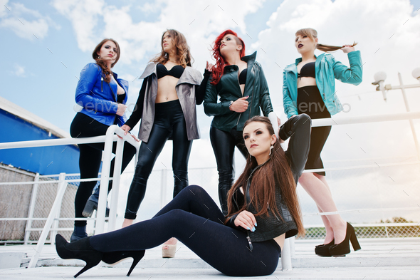 Group of sexy models girls in black bra and leather jackets on the dock