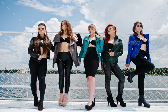Group of sexy models girls in black bra and leather jackets on the dock