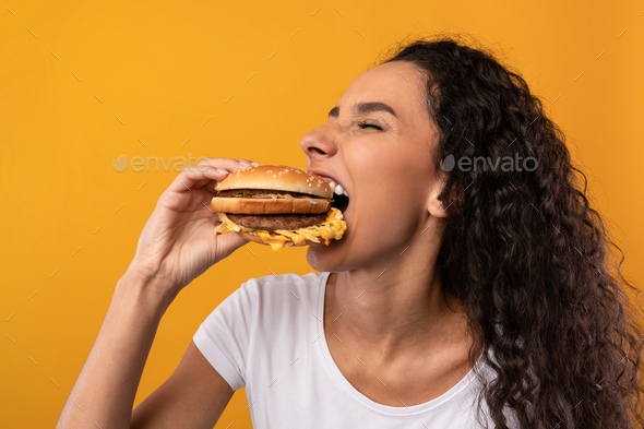 Funny Hungry Latin Lady Holding Burger Biting Sandwich At Studio