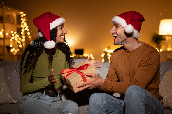 Couple Celebrating Xmas, Man Giving Gift To Wife At Home