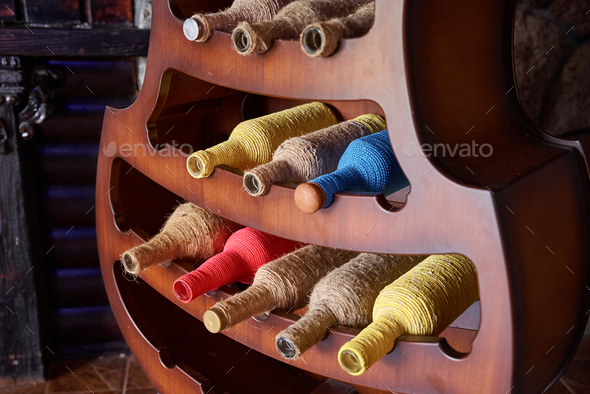 Colorful wine bottles wrapped in a rope on stand. Interior design element