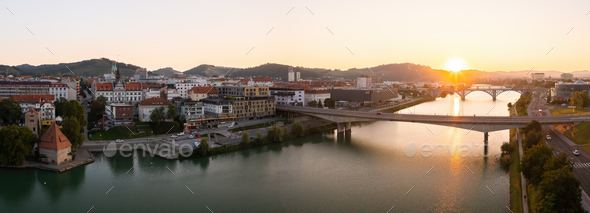Drava river flowing under bridges of Maribor city with sun rising in background