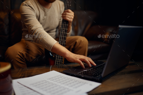 Young man learning playing guitar through internet
