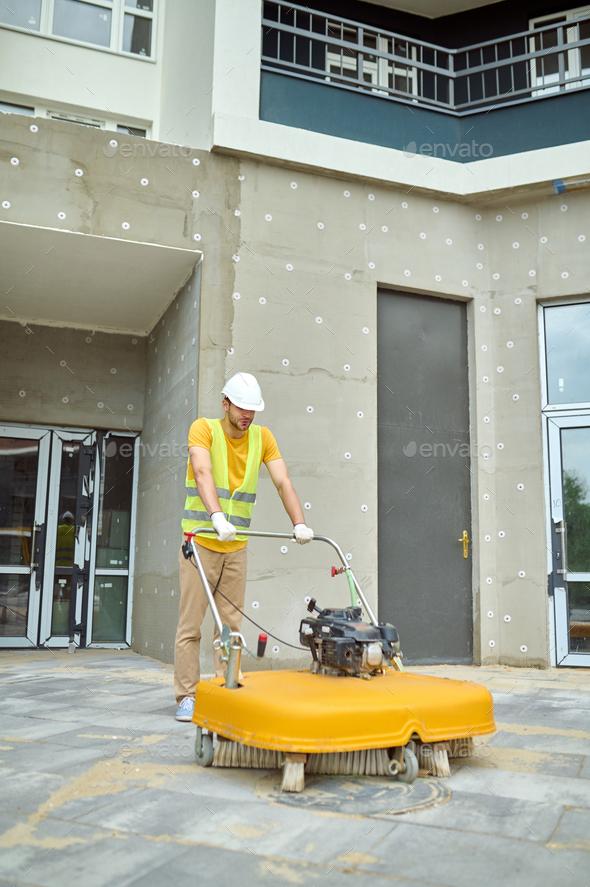 Man operating special equipment cleaning construction site