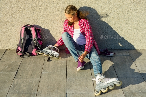 Teen girl removes sneakers and clothes roller skates outdoor