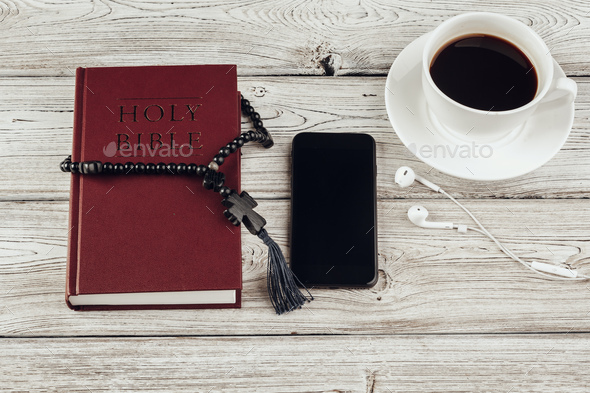Holy Bible and smartphone with black coffee cup on wooden background
