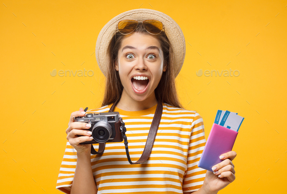 Girl with retro camera, pasport and airplane tickets shocked with good commercial offer