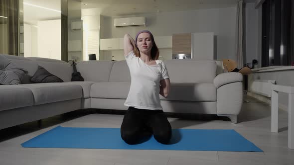A Girl in a White Tshirt and Black Sports Pants Doing Yoga and Stretching