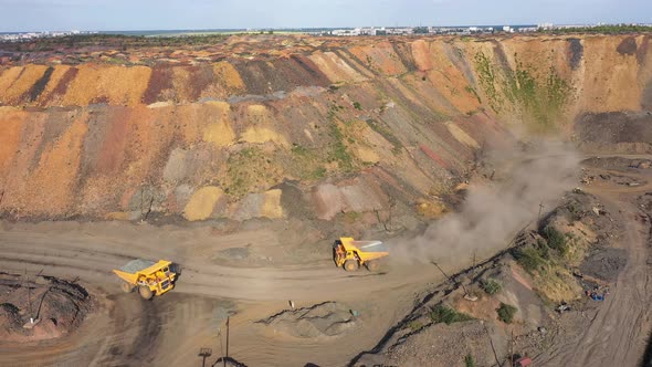Two Large Mining Dump Truck Going to Meet Each Other on a Dusty Road alt
