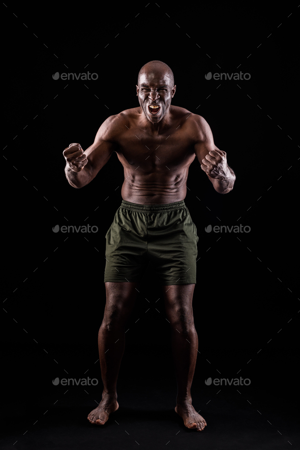 African American man facing front with fists clenched and shouting at camera
