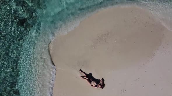 Aerial View of a Beach Surrounded By Waves with a Woman Sunbathing Lying on a Sand