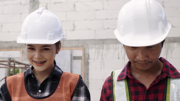 Portrait of Asian construction worker at building site smiling at camera alt