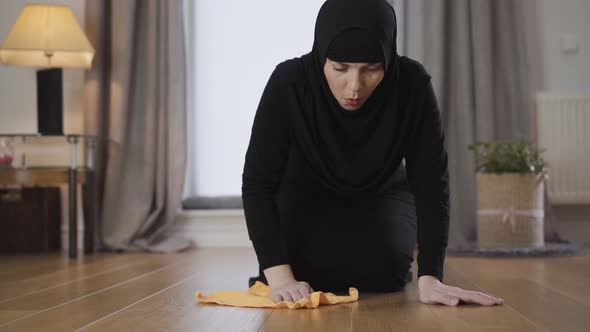 Close-up of Young Muslim Lady in Hijab Cleaning the Floor with Yellow Rag. Diligent Eastern alt