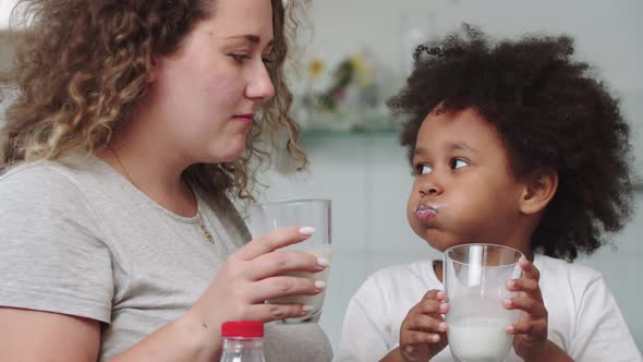 White Mother and Her Mixed Black Daughter Drinking Milk at the Kitchen alt