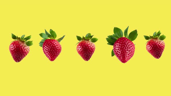 funny movement of many fresh red strawberries close-up on a yellow background alt
