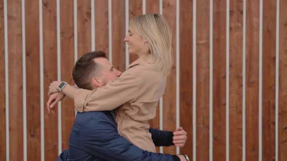 Young Man and Woman Are Meeting on Street Man Is Lifting Girl on Hands alt