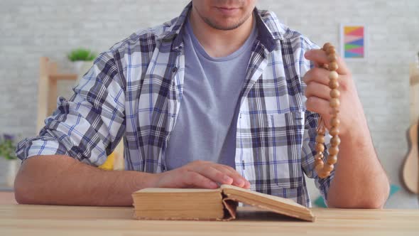Close Up of a Young Man with a Rosary in His Hands Reading the Bible alt