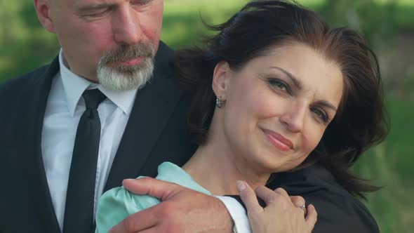 Zoom in to Confident Smiling Happy Woman Posing in Slow Motion Outdoors As Man Hugging Spouse alt