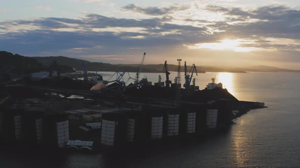 Silhouettes of Cargo Cranes Working in the Early Morning at Dawn in the Port alt