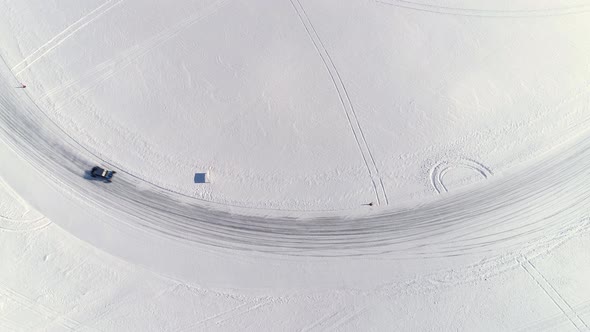 Observed from high above, a custom built utility vehicle drifts around an icy corner on a frozen rac alt